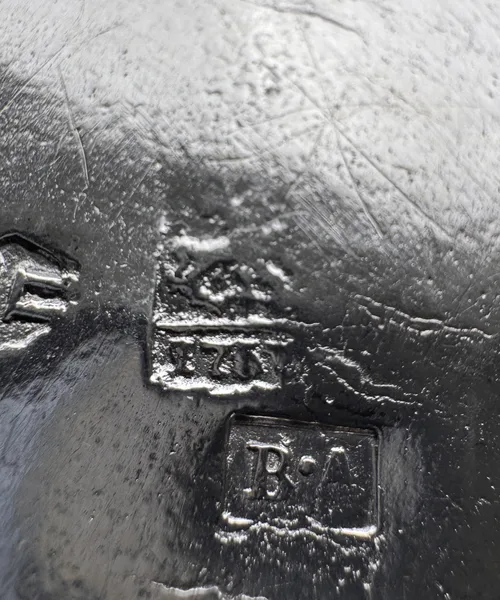 Groupe de poinçons bruxellois du XVIIIe siècle à déchiffrer à la loupe sous une pièce en argent